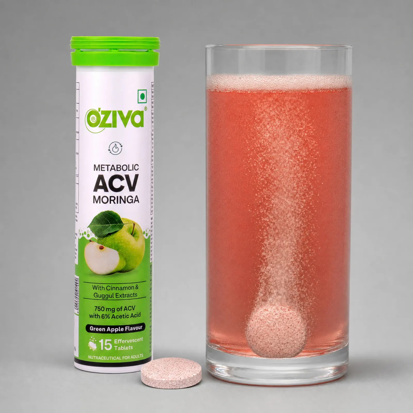 The tube next to a glass where a tablet dissolves and turns the water pink